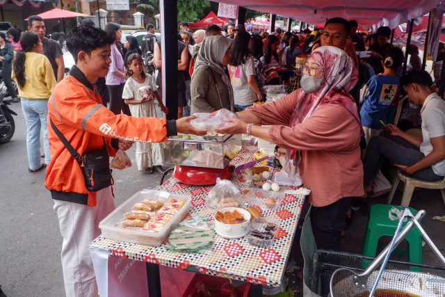 Seorang kurir Shopee menerima orderan di Pasar Takjil Ramadan, Jalan Andi Mappanyukki, Makassar.